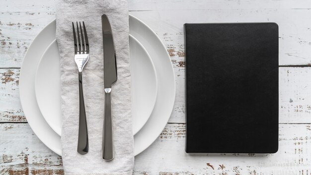 Top view of menu book with plates and cutlery