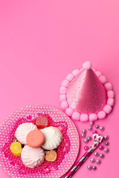 분홍색, 마시멜로 설탕 달콤한 색상의 생일 휘파람 및 생일 모자와 함께 접시 내부의 상위 뷰 머랭과 마멀레이드