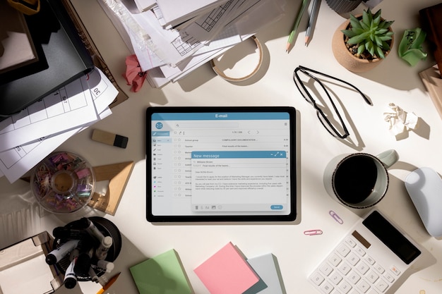 Foto gratuita vista dall'alto dell'area di lavoro disordinata dell'ufficio con tablet