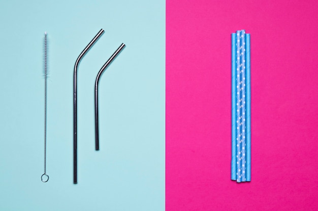 Top view metallic and paper straws on bicolored background
