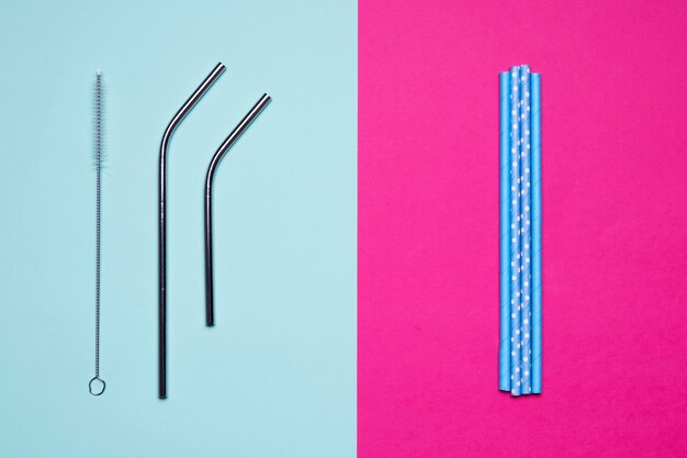 Top view metallic and paper straws on bicolored background