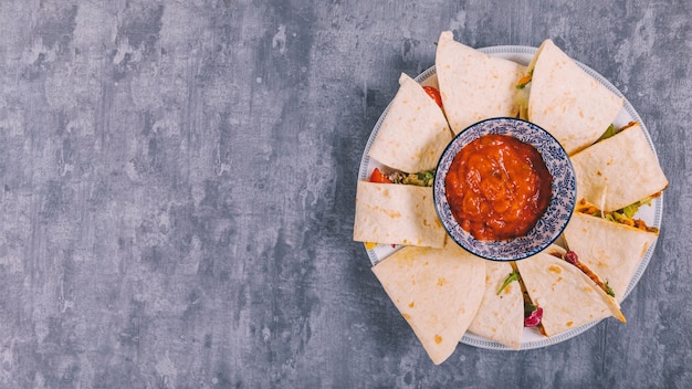 Top view of mexican beef tacos with salsa sauce in plate over concrete floor