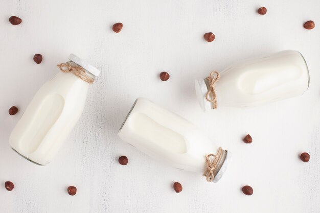 Top view milk bottles and hazelnut background