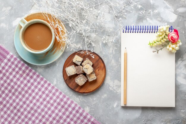 Top view milk coffee with waffles and notepad on the light desk coffee milk chocolate cookie