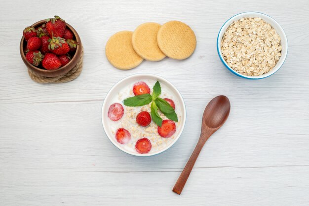 白、朝食用シリアルの健康上のクッキー、新鮮なイチゴと一緒にイチゴとプレート内のオートミールとトップビューミルク