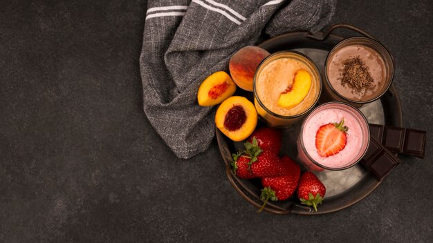 Top view of milkshake glasses with fruits and chocolate