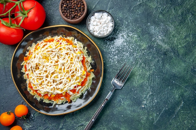 top view mimosa salad inside plate with seasonings and tomatoes on dark blue background