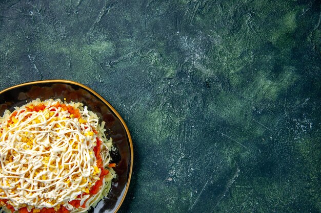 top view mimosa salad with eggs potato and chicken inside plate on dark blue background