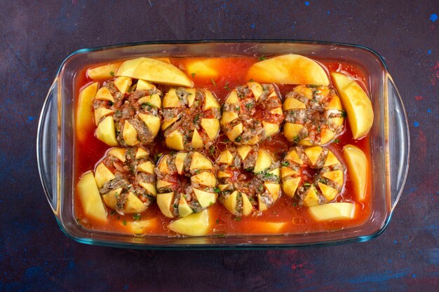 Top view of minced meat inside potatoes on the dark purple surface