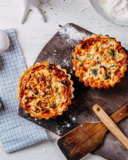 Вид сверху мини пирог с мясом и овощами на деревянной разделочной доске