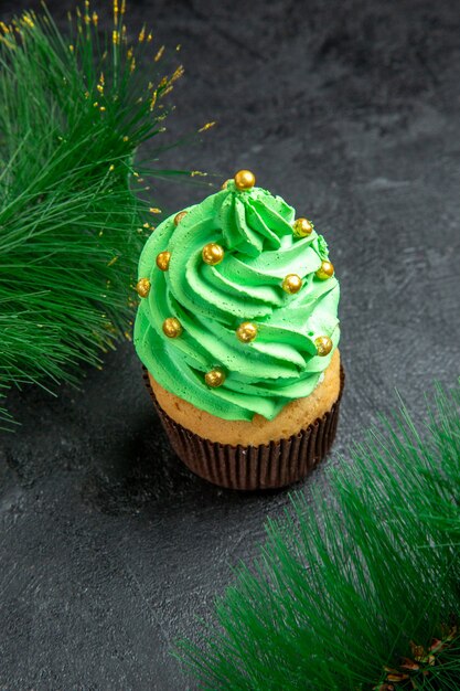 Top view mini xmas tree cupcake and xmas tree branches on dark surface