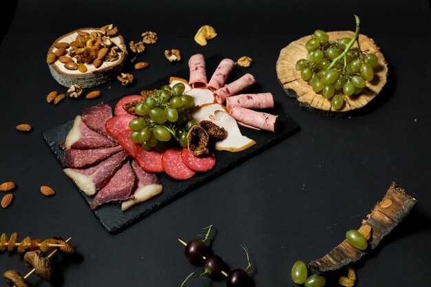 Top view misnaya plate with grapes and nuts on a stand with dried fruits on a black table