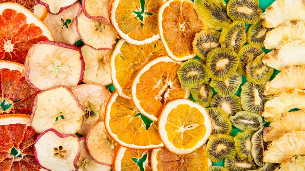 ドライフルーツと柑橘類のミックスのトップビュースライスアップルオレンジキウイとドライフルーツと柑橘類のパイナップルの背景