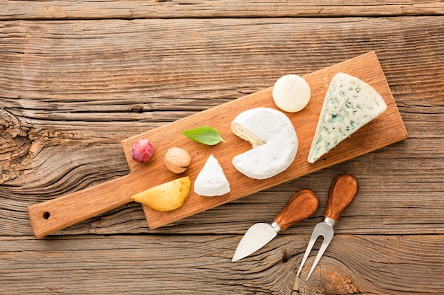 Top view mix of gourmet cheese on wooden cutting board