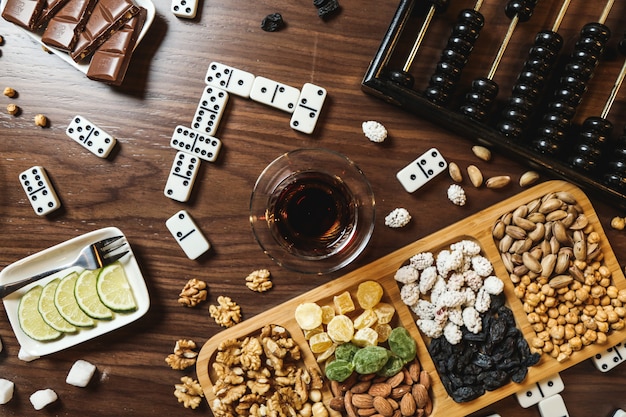 Top view mix of nuts with tea lemon slices chocolate bar dominoes and abacus on the table