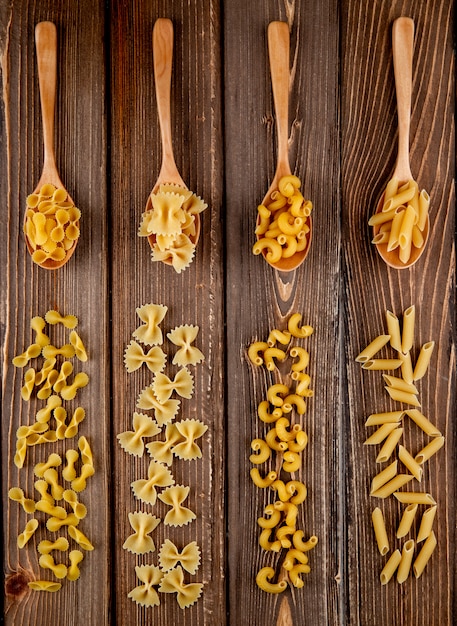 Vista superiore mix pasta farfalle gomito penne maccheroni e farfalle tonde pasta su fondo di legno