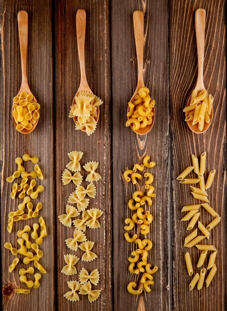 Top view mix pasta farfalle elbow macaroni penne and farfalle tonde pasta on wooden background