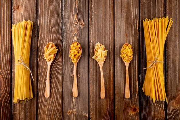 Вид сверху смесь макарон спагетти букатини Фарфалле Пенне локоть макароны и фарфалле тонде на деревянном фоне