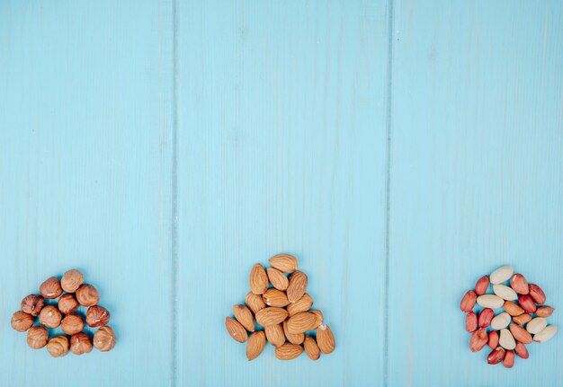 Vista superiore del misto di mucchio di noci isolato su sfondo blu mandorle nocciole e arachidi con spazio di copia