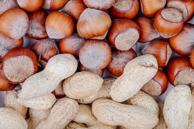 Top view of mixed nuts in shell hazelnuts and peanuts on white background