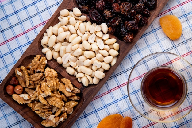 Free photo top view of mixed nuts with dried fruits in a wood box served with tea in armudu glass on the tablecloth