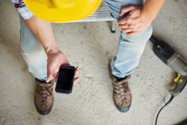 Top view on mobile phone used by manual worker