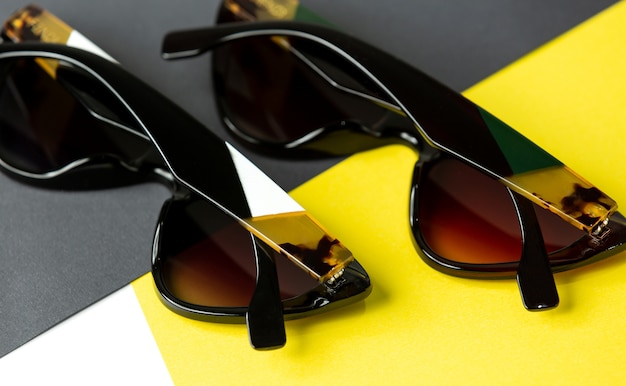 A top view modern black sunglasses pair on the yellow-black background isolated vision spectacles elegance