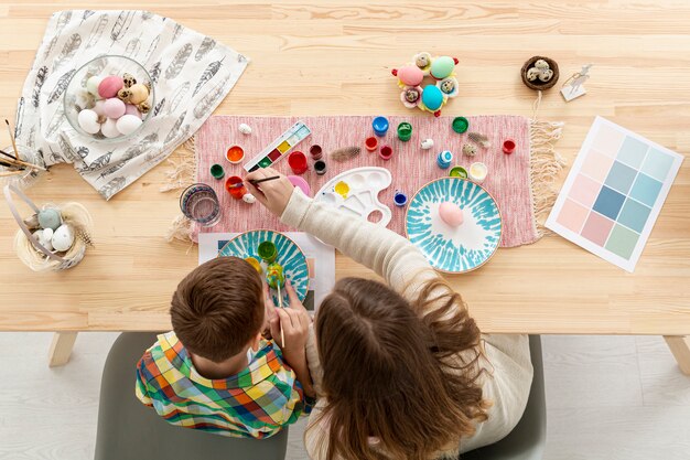 Top view mother and son painting eggs