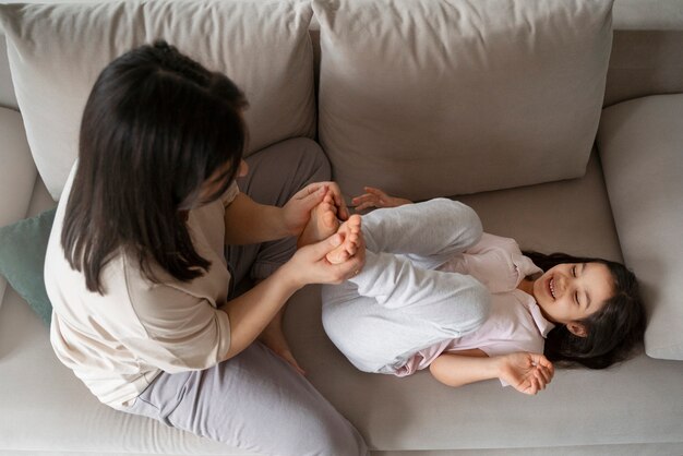 Top view mother tickling kid on couch