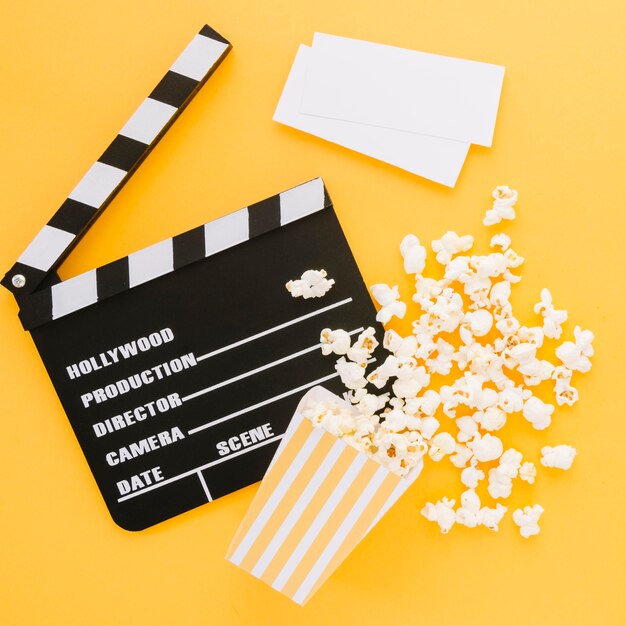 Top view movie clapperboard with tasty popcorn