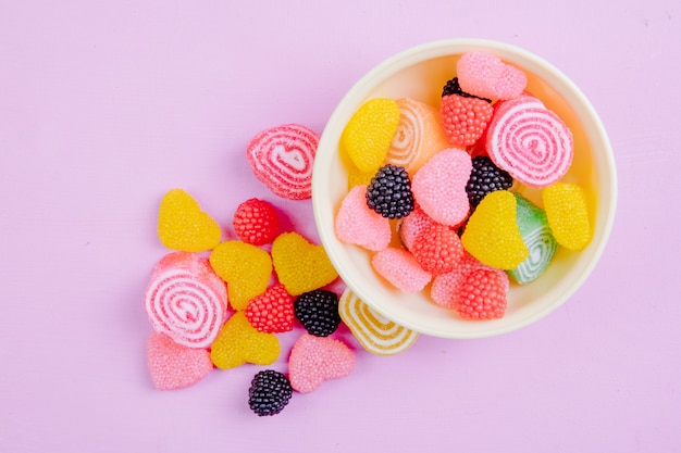 Top view multi-colored marmalade in different forms on a light pink background