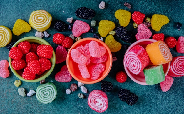 Vista dall'alto marmellate multicolori in diverse forme in piattini per marmellata su uno sfondo verde scuro