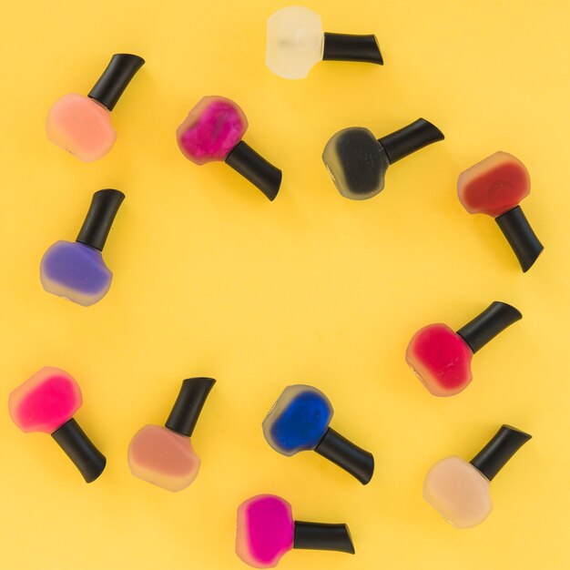 Top view of multi colored nail varnish on yellow background