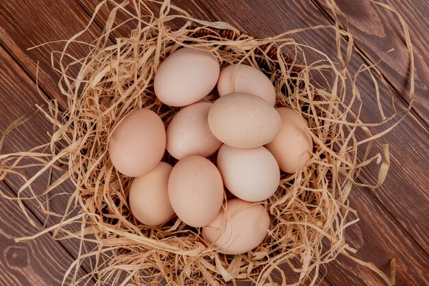 Top view of multiple chicken eggs on nest on a wooden background