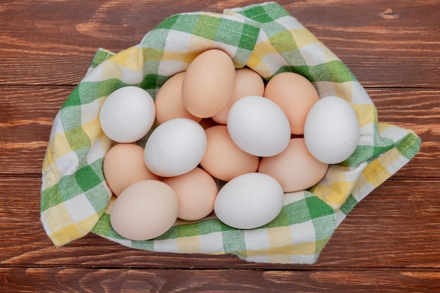 나무 배경에 체크 식탁보에 여러 신선한 닭고기 달걀의 상위 뷰