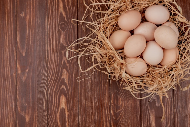 Top view of multiple fresh chicken eggs on nest on a wooden background with copy space