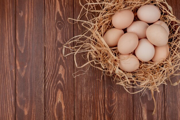 Top view of multiple fresh chicken eggs on nest on a wooden background with copy space