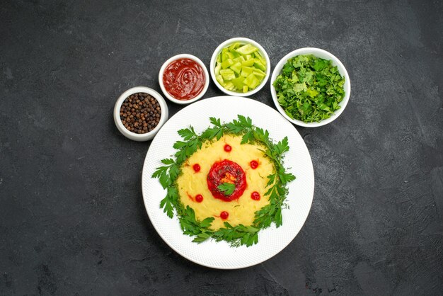 Top view of mushed potato dish with greens on dark