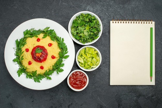 Free photo top view of mushed potato dish with tomato sauce and greens on dark