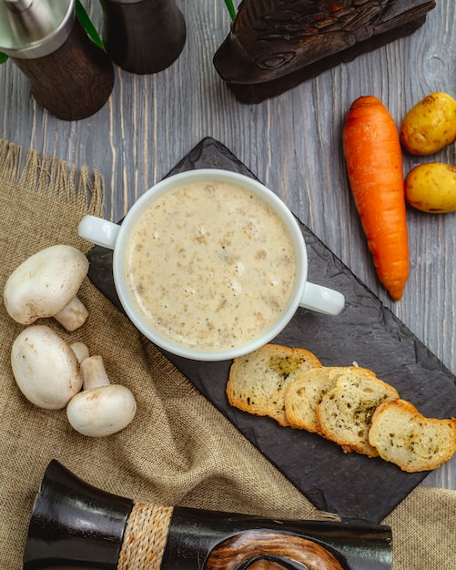 Top view of mushroom cream soup in a white bowl with toasts