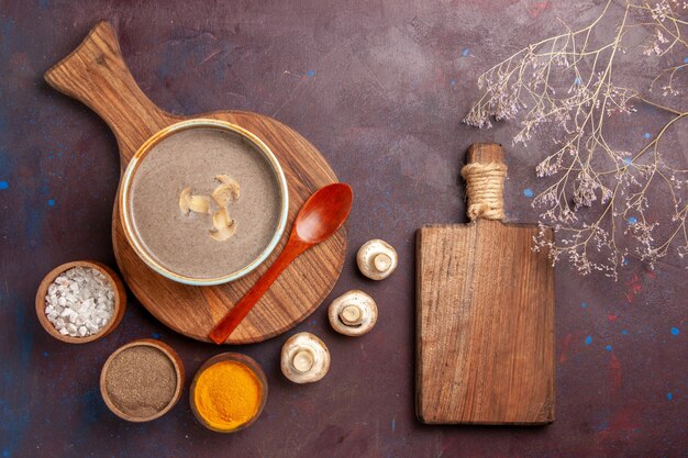 Top view mushroom soup with different seasonings on dark space