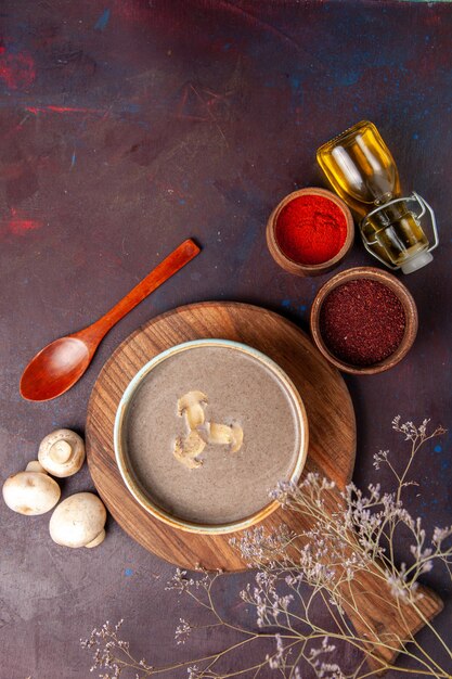 Top view mushroom soup with different seasonings on dark space