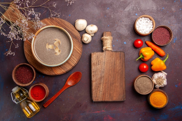 Top view mushroom soup with different seasonings on the dark space