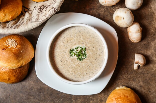 Top view mushroom soup with a loaf of bread on the table