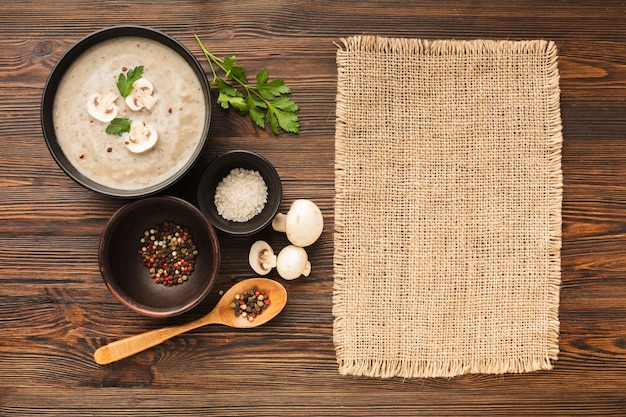 Top view mushrooms bisque condiments and spoon with textile material