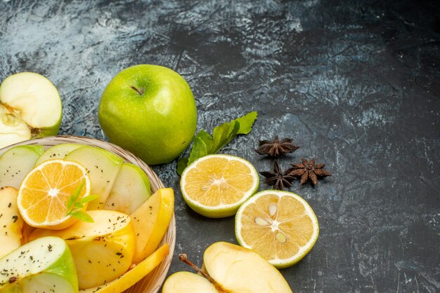 Top view of natural apples lemon on a white plate and cinnamon limes kumquats oranges on dark table