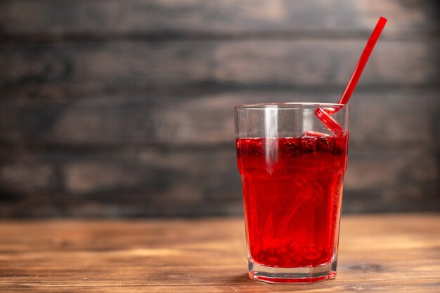 Top view of natural organic fresh currant juice in a glass served with a tube on the left side on a wooden table