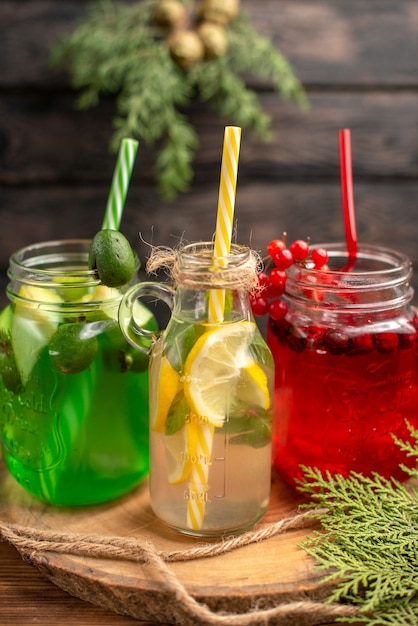 Free photo top view of natural organic fuit juices in bottles served with tubes on a wooden cutting board