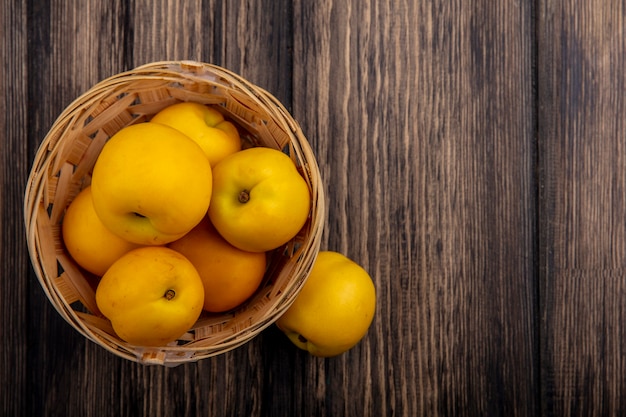 Top view of nectacots in basket and on wooden background with copy space