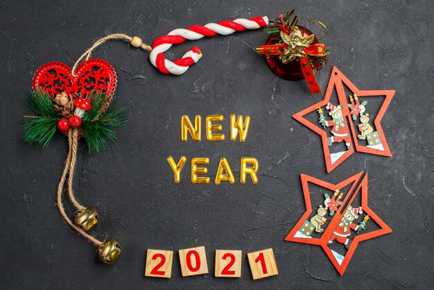 Top view new year in a circle of different xmas ornaments candy wood block on dark isolated surface